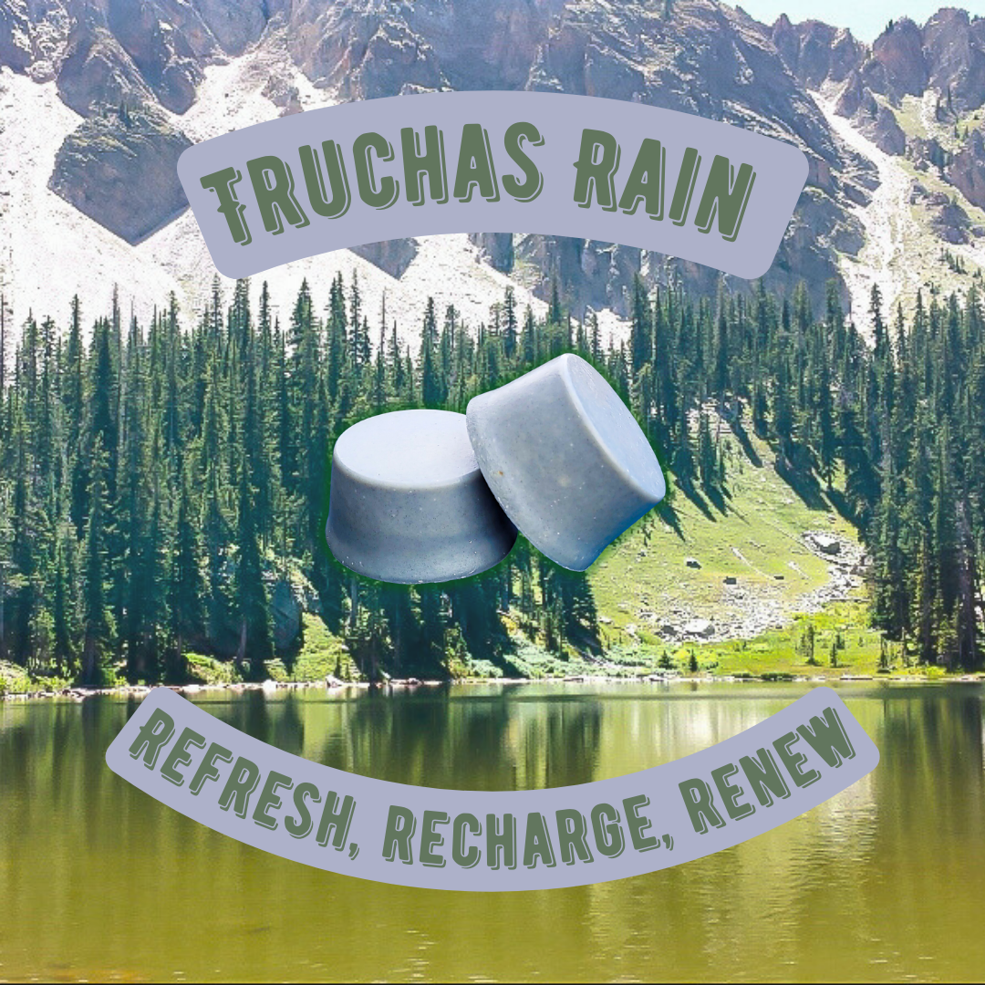 A promotional image featuring two bars of soap with the text 'TRUCHAS RAIN REFRESH, RECHARGE, RENEW' overlayed on a background showing a lake and mountain landscape.